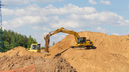 Fototapeta na wymiar large excavator strews yellow sand