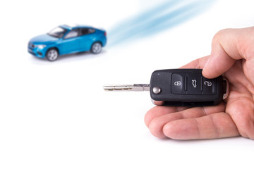 Car key in the hand. Blue car in the background