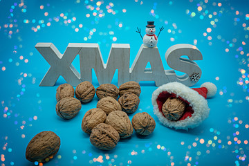 christmas Schriftzug mit Schneemann, Walnüssen und Schnee auf blauen Hintergrund