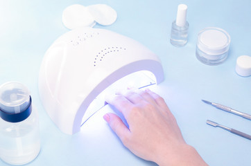 Nail extension on a female hand with a gel and an ultraviolet LED lamp on a streak