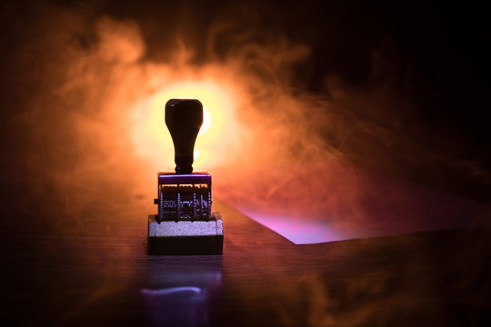 Close up view of rubber date stamper on wooden table with dark toned foggy background.