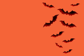 Halloween and decoration concept - bats fly over an orange background