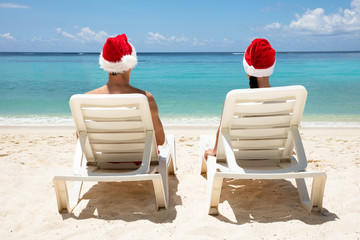 Young Couple Sitting On Deck Chair At Beach