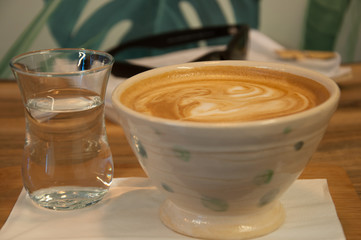 Cup of capuchino in a custom cup with glas of water. Close up.