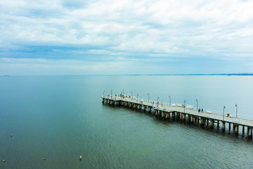Fototapeta na wymiar Aerial view of a wooden pier and a beach in the city of Gdynia-Poland. Drone shot on a long sea pier in the Baltic Sea. 