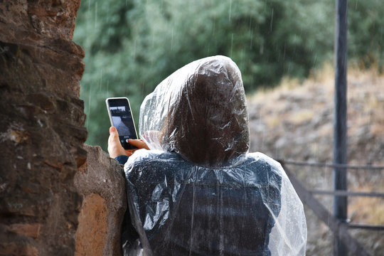 Woman taking pictures using cell phone in the rain