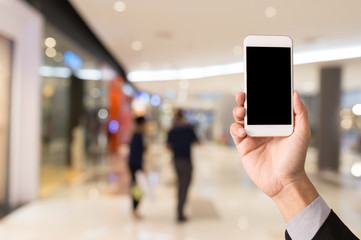 Hand hold blank smartphone on blur shopping mall background