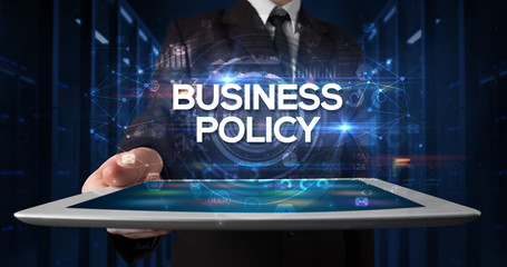 Young business person working on tablet and shows the inscription: BUSINESS POLICY, business concept