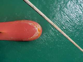 Top view of the moored vessel bulbous bow with scratches and mooring rope crossing the picture.