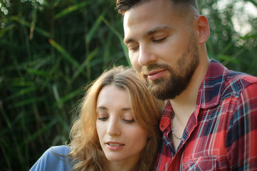 Fototapeta premium Close up portrait of young couple hugging on green stems background, hipsters concept
