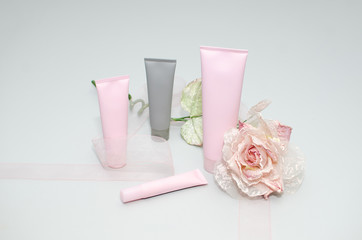 Tube for cosmetics with ribbon,  pink gray, isolated on white background.