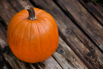 Top view on an orange helloween pumpkin on a wooden board -Autumn, Helloween, agriculture concept.