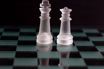 White queen and king chess pieces on a black background