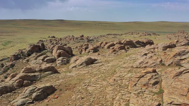 Aerial around view on rock formations and steppe, Baga Gazriin Chuluu, Gobi desert, Mongolia, 4k