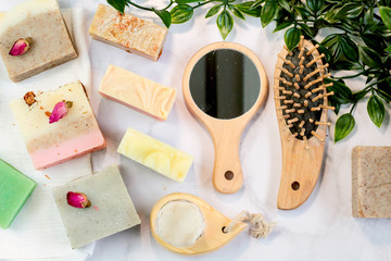 handmade multicolored soap with herbs and rosebuds, comb, towel, mirror, face brush on a marble background with. Spa set kit for face and body treatments flat lay  style