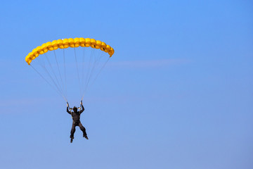 Skydiver with yellow parachute in blue sky