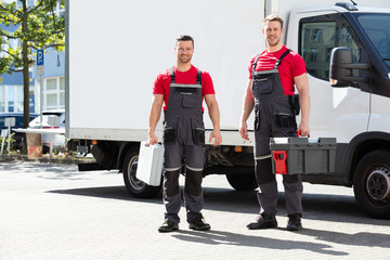 Portrait Of A Smiling Young Male Technicians Holding Tool Box