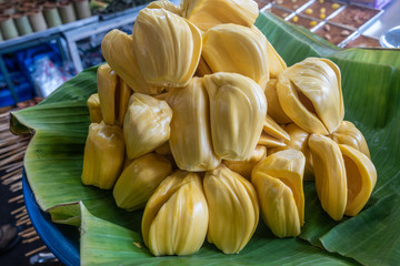 Chon Buri, Thailand - March 16, 2019: Closeup of Heap of peeled yellow jack fruit displayed on green banana leaf at stret market on Sukhumvit Road.