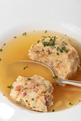 single speckknoedel in soup on wood