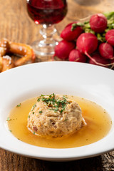 single speckknoedel in soup on wood