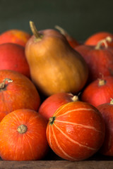 A lot of red ripe pumpkins on a old wooden green background close up, holiday halloween. Pile of ripe pumpkins. Harvest autumn wallpaper