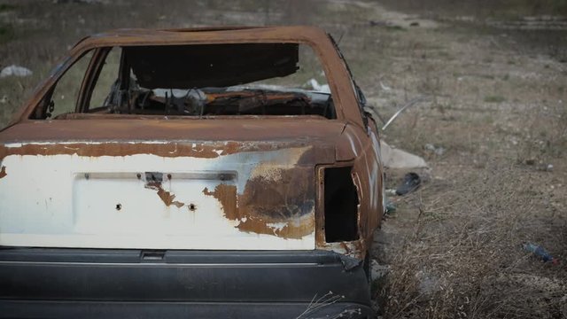 Old rusty broken car in a landfill. Rusty burnt car in a junkyard.