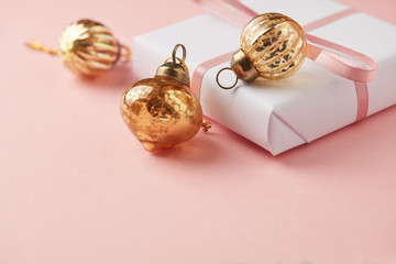 Christmas baubles and Christmas present. Pink paper background. Close up. Copy space. 