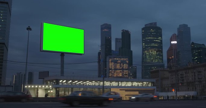 Large billboard with a green screen, a megapolis highway with neon lights, skyscrapers on background, city traffic at night