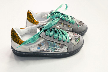Pair of trendy creative sneakers, with green shiny laces on a white background. Youth style