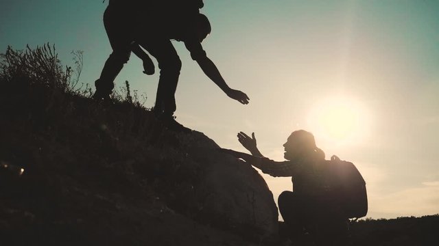 teamwork help business travel silhouette slow motion video concept. Helping hand silhouette between two climbers. teamwork group of tourists lends a helping hand climb the cliffs mountains. couple man