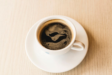 Hot black coffee in a white cup on table