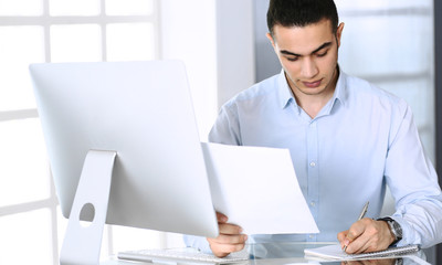 Businessman working with computer in modern office. Headshot of arab male entrepreneur or manager at workplace. Business concept