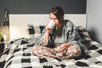 Young beautiful Caucasian woman has a cold, flu with high fever and heat at home in bed. The girl...