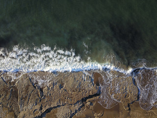 Obraz na płótnie Canvas Aerial photograph of a rocky coastline with arriving and breaking ocean waves in Bilbao Spain