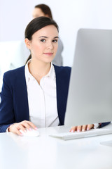 Business woman working with computer in office, female colleague at background. Headshot of Lawyer or accountant at work while sitting at the desk