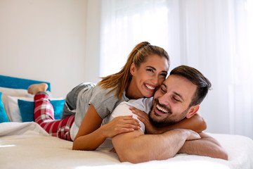 Happy couple is lying in bed together. Enjoying the company of each other. Sensual romantic foreplay by couple in love in bed. Happy young couple in bed. Couple making love
