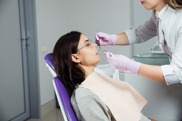 Obraz premium A woman is preparing for a dental examination. Woman having teeth examined at dentists. 