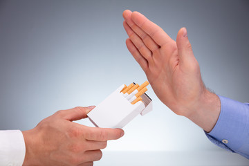 Man's Hand Refusing Cigarette Offer By Other Person