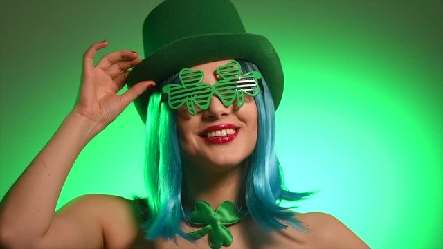 St. Patrick's Day leprechaun model girl in green hat and costume over green background, Dancing on party, Smiling. Patrick Day pub party, celebrating. Green beer. Ads. 4K UHD slow motion