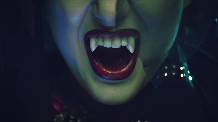 Sexy Vampire Woman's red bloody lips close-up. Vampire girl licking fangs with tongue. Fashion Glamour Halloween art design. Close up of female vampire mouth, teeth. On black background 4K UHD video