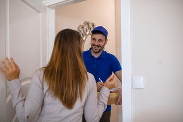 Woman receiving a package at home from a delivery guy. Woman receiving package envelope from delivery service courier indoors, closeup. Express Delivery. Courier Delivering Package