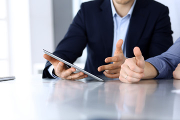 Business people using tablet computer while working together at the desk in modern office. Unknown businessman or male entrepreneur with colleague at workplace. Teamwork and partnership concept