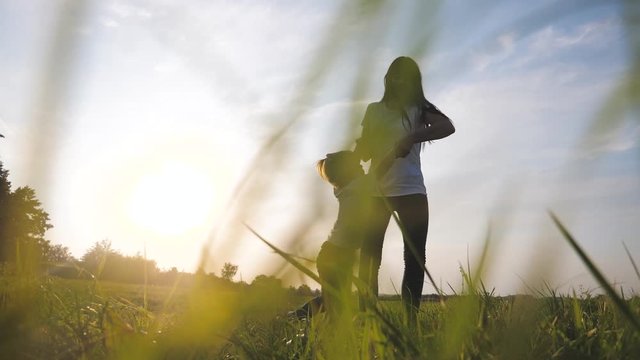 happy family a mom is circling a little daughters hands hold hand slow motion video. adult woman and little girl playing in white t-shirts outdoors lifestyle