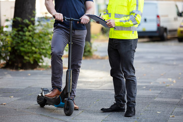 Officer Standing Near The Man On Electric Scooter