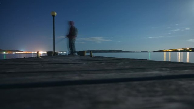 timelapse hyperlapse of anonymous fisherman spinning eging catching squid octopus cuttlefish at sunset star night sky