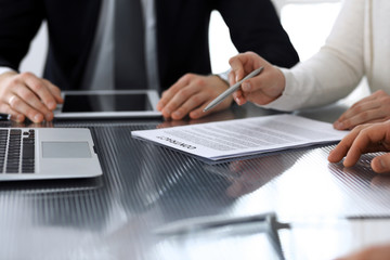 Business people discussing contract working together at meeting at the glass desk in modern office. Unknown businessman and woman with colleagues or lawyers at negotiation. Teamwork and partnership