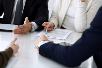 Business people discussing contract working together at meeting at the glass desk in modern office. Unknown businessman and woman with colleagues or lawyers at negotiation. Teamwork and partnership