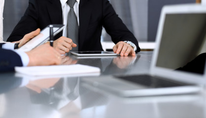 Business people discussing contract working together at meeting at the glass desk in modern office. Unknown businessman and woman with colleagues or lawyers at negotiation. Teamwork and partnership