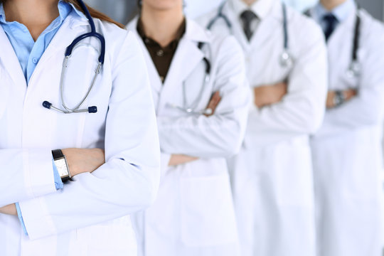 Group of modern doctors standing as a team with arms crossed in hospital office. Physicians ready to examine and help patients. Medical help, insurance in health care, best desease treatment and