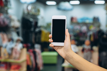 Hand using smartphone for doing business or banking or buying online on blur shopping mall background